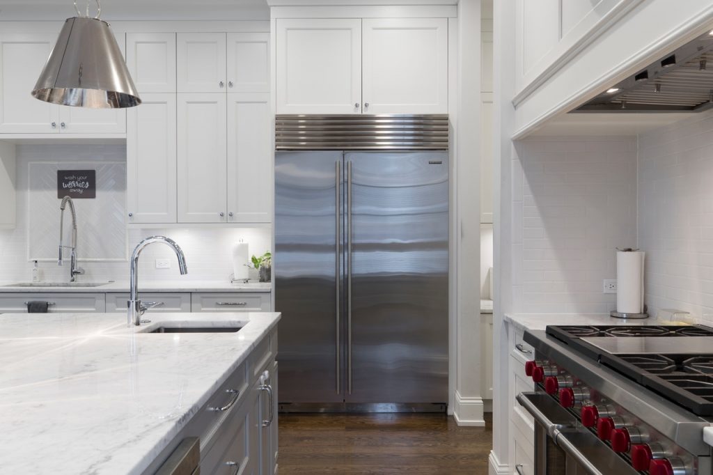 Stainless steel refrigerator beside white kitchen cabinet.