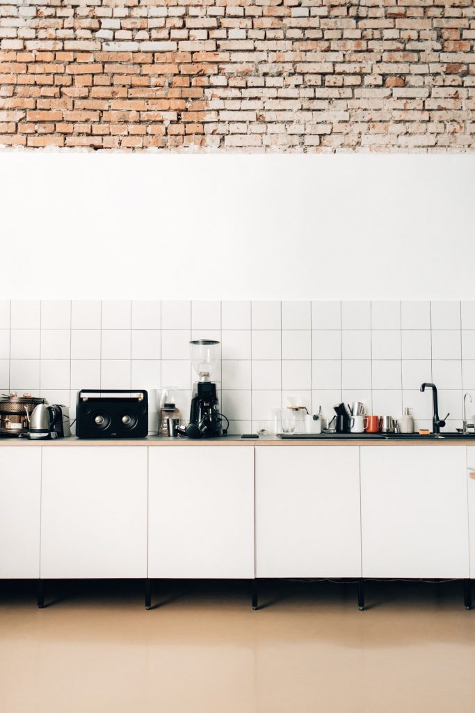 Small kitchen appliances on white wooden kitchen cabinets.